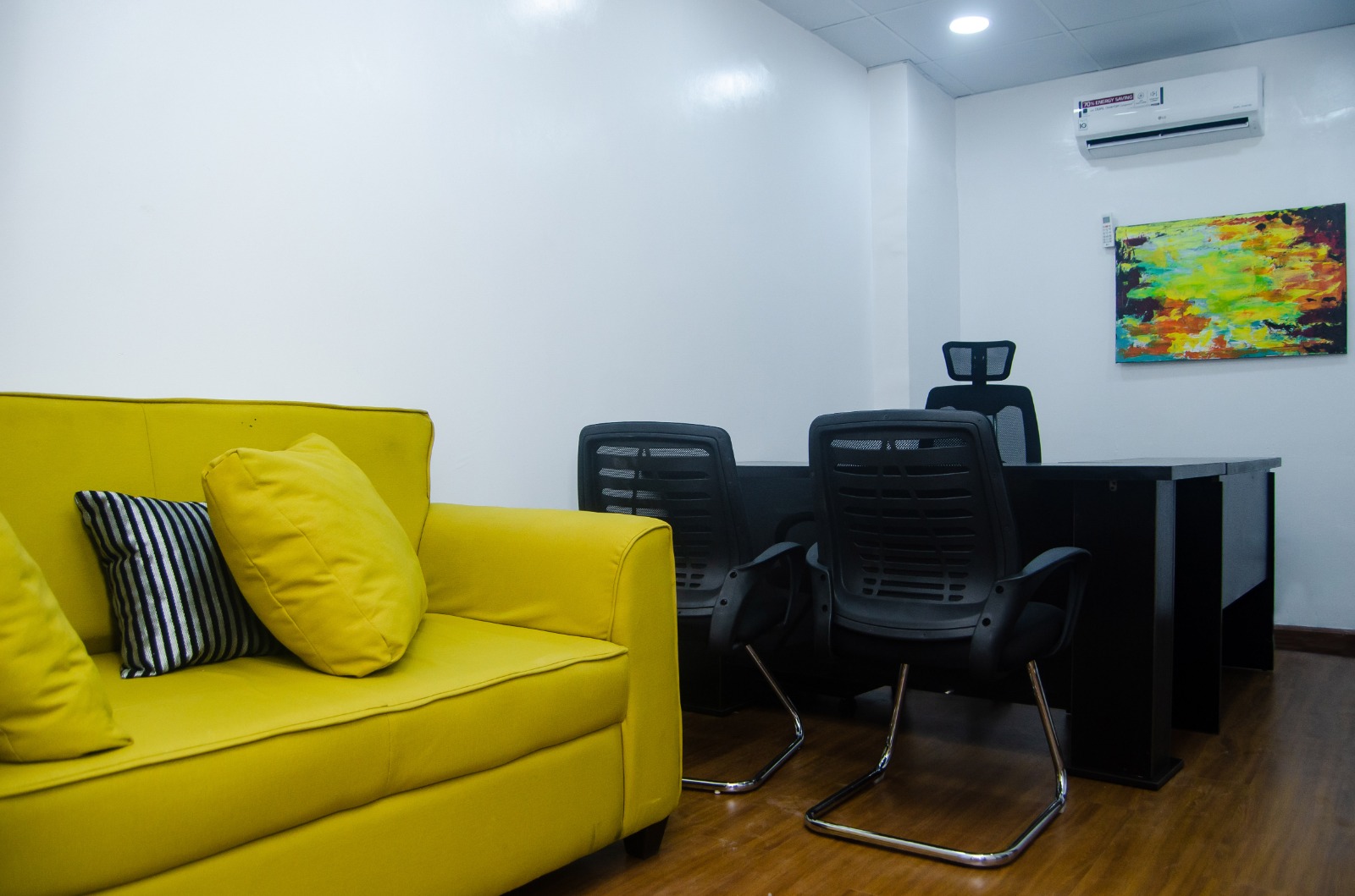 Workspace with yellow sofa, desk, and wood flooring