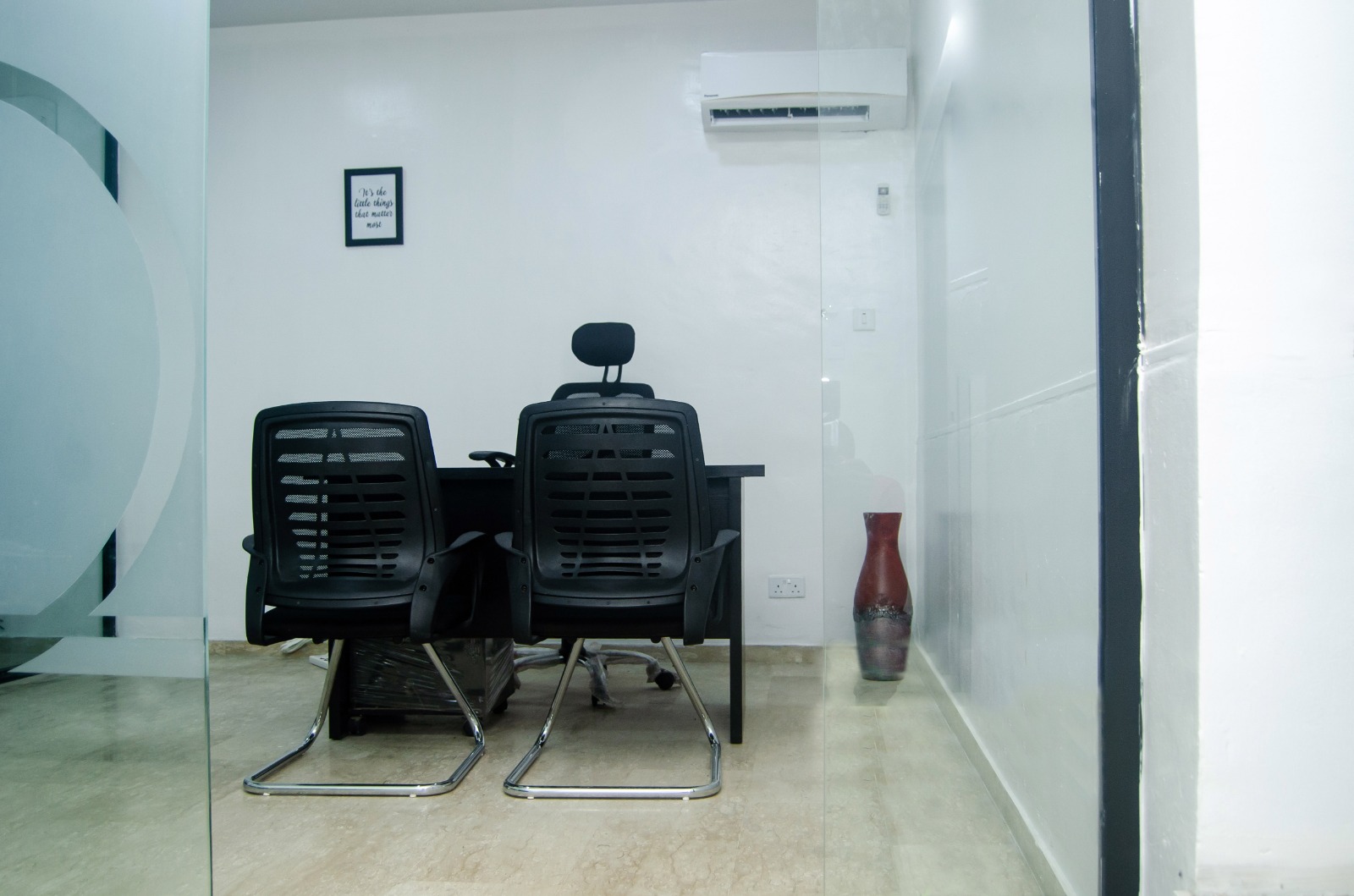 Office seen through glass with chairs and a vase